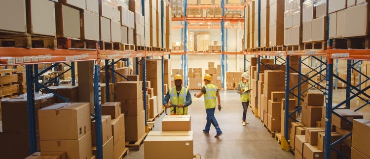 Three associates stocking boxes onto shelves in a warehouse