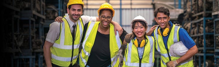 Four warehouse associates smiling for a picture in their uniform