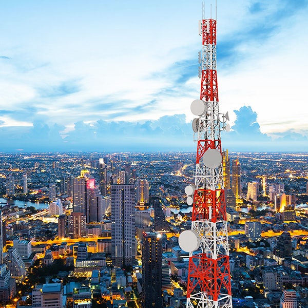 Red and white telephone tower looking over a city at night