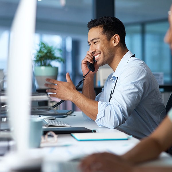A male tech support associate talking on the phone and smiling