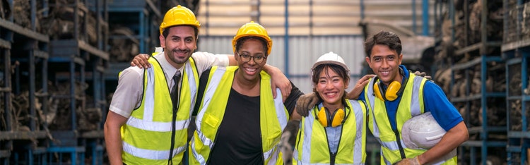 Four warehouse associates smiling for a picture in their uniform