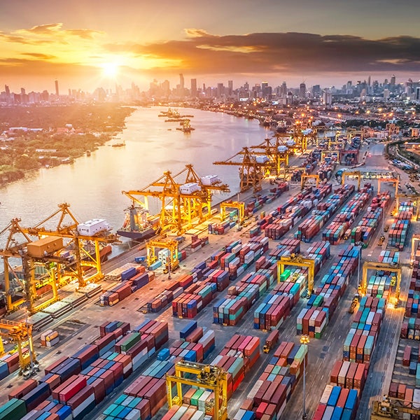 A landscape of a cargo yard with a city skyline in the background during a sunset